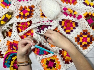 Crocheting granny square blanket process and woman's hands hobby handmade handiwork clews and hook cozy winter autumn fall photo