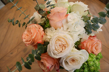 A close-up of delicate peach-colored roses with intricate, layered petals, arranged in a bouquet and wrapped in soft floral-themed paper, radiating natural elegance and beauty.