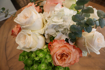 A bouquet of peach-hued roses with intricate, layered petals, beautifully arranged and wrapped in soft floral-patterned paper, radiating elegance and timeless natural charm.