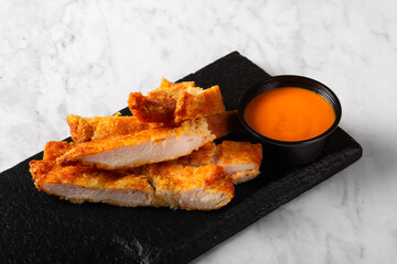 Crispy Chicken Tenders on a Black Stone Over Marble Surface