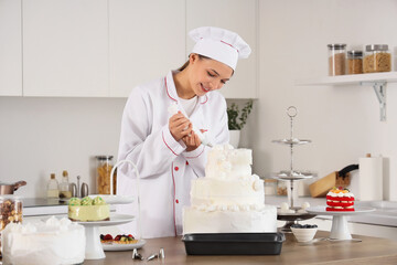 Female confectioner making cake with cream in kitchen