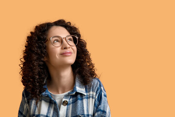 Young woman looking upwards on orange background, closeup