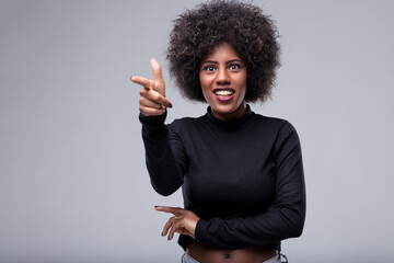 Young woman pointing finger and smiling at the camera