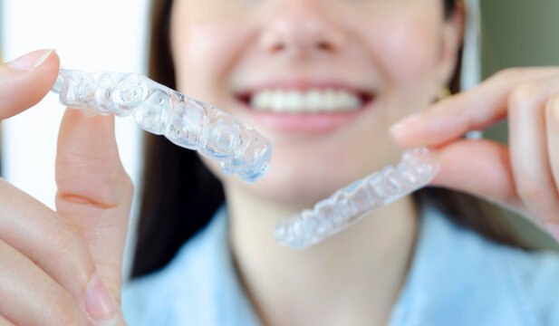 Chica mostrando alineadores transparentes invisalign. Ortodoncia invisible. Aparatos dentales removibles. 