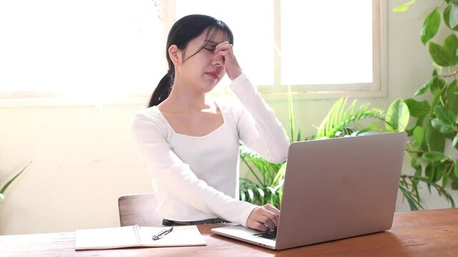 ノートパソコンの前で困る若いアジア人女性