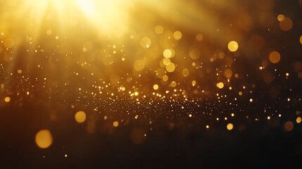 Fototapeta premium Golden glittering dust particles illuminated by a bright light source on a dark background.
