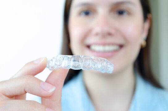 Mujer sosteniendo alineador invisible superior. Tratamiento de ortodoncia invisalign removible. 