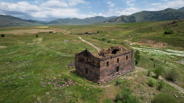 Forward reveal aerial shot of Saint Paul and Peter (Surb Pogos Petros) Church on a sunny spring day. Aparan Reservoir, Armenia.