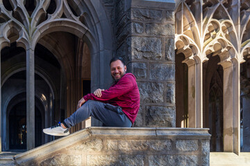 A man in a red hoodie is sitting on a stone ledge