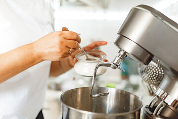Middle aged asian woman preparing dough in the kitchen at home with mixer. Home baking for the whole family. 