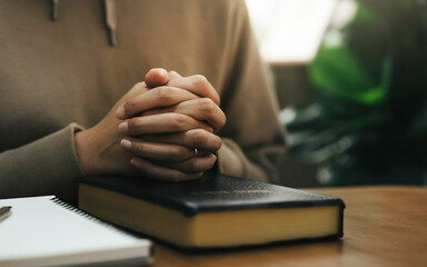 Christian hand pray and worship to god with Holy bible and cross on a wooden table in church. praying concept. spirituality and religion