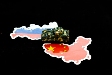 Miniature toy tank on maps of Russia and China with Flags colors and design. Geopolitical alliance...