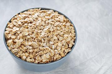 Bowl of Raw Rolled Oats on Textured Gray Background, Healthy and Nutritious Breakfast Ingredient, Copy Space