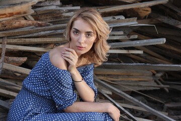Abstract portrait of a romantic girl in a blue dress on the background of a sawmill.
