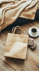 Naklejka premium A brown paper shopping bag, a cup of coffee, and a cozy knit blanket lie on a wooden floor.