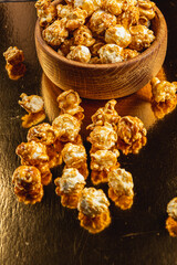 Sweet caramelized popcorn in a wooden bowl on a golden background