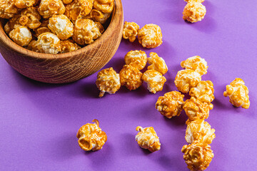 Sweet Caramelized Popcorn in a Wooden Bowl on a Purple Bright Background
