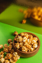 Snack concept Sweet caramelized popcorn in a wooden bowl on a green background