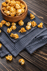 Snack concept, caramelized popcorn in a wooden bowl on a gray, wooden background