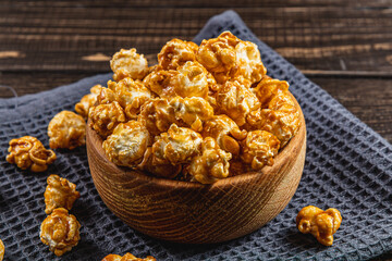 Snack concept, sweet caramelized popcorn in a bowl on a gray, wooden background