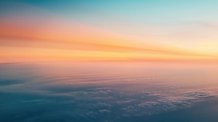 Fototapeta premium an abstract photograph of the horizon, the sky is orange and blue with some clouds, the ocean below has a slight fog over it
