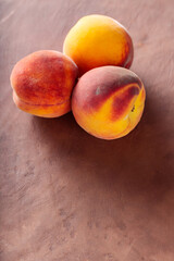 Fresh Ripe Peaches on Textured Brown Surface with Dramatic Shadows, Top View, Copy Space