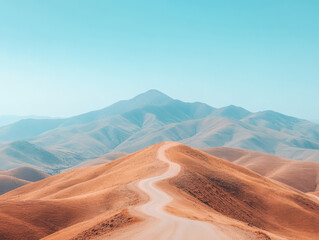 Naklejka premium Scenic winding road through golden hills under clear blue sky in a serene landscape