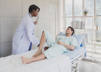 Obraz premium Patient caucasian man lying bed with woman doctor black people stand carer physical therapist two person talk help support and check treat sick person take care of your health in room hospital clinic