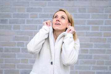 Woman Looking Upward Brightly.A blonde woman in a white coat gazes upward with a radiant and hopeful expression..