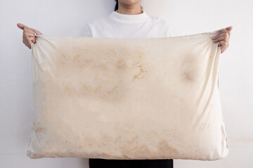 Old pillow with yellow and dirty stains,woman holding a dirty pillow with sweat stains and saliva...