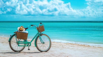 Fototapeta premium A teal bicycle with a straw hat and basket rests on a sandy beach overlooking a turquoise ocean. Beautiful scenery of a tropical paradise.