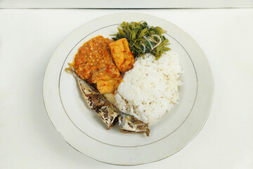 Rice mixed with fried fish and tempeh vegetables on a white plate, on the table