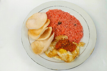 Red fried rice, fried egg and crackers on a white plate
