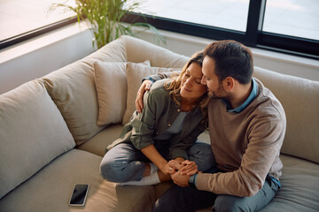 Affectionate couple embracing while relaxing on sofa.