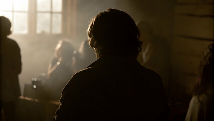 Silhouette of person in dimly lit room with warm backlighting