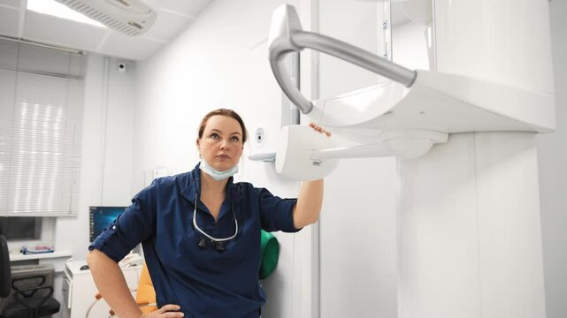 Modern equipment in dentistry, professional dentist woman in medical office. Skilled stomatologist or orthodontist preparing tomographic scanner, portrait of health professional, healthcare, medicine