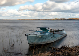 Obraz premium boat on the lake shore, during a storm, blurred outlines of water and grass