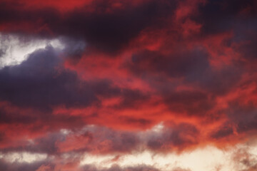 Fototapeta premium Drama in the Predawn Sky - A tranquil morning sky becomes illuminated by the approaching sunrise’s fiery hues of blood red and vibrant orange, creating a dramatic cloudscape.