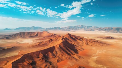 cinematic photography drone angle looking down on to dusty arid desert, vibrant red sand, epic view, blue sky