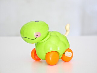 the toy is green and has an orange wheel with a white background