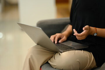 Cropped shot young woman speaking during video call on her laptop at home