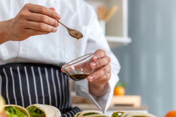 Chef is pouring a sauce into a bowl