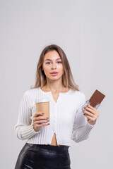 Attractive brunette young woman holding a cofee cup and chocolate on a white background. Copy space, close-up portrait