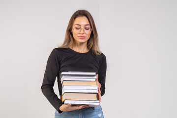 Young cute smiling girl with a stack of books on a white background. Copy space