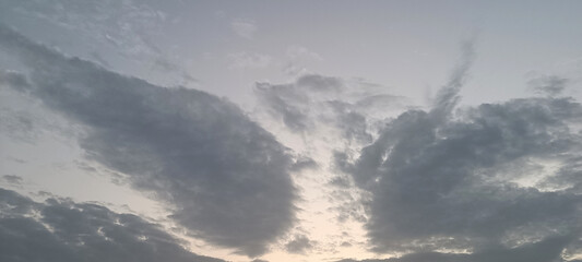 Obraz premium Dramatic clouds fill the sky, with a subtle gradient from light to dark. The soft lighting hints at either sunrise or sunset, creating a serene and atmospheric scene.