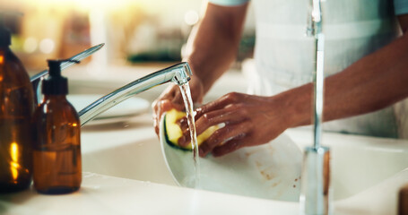 Man, hands and washing dishes in kitchen for responsibility, dirt removal and hygiene with foam. Person, plate and water in home for bacteria prevention, cleaning or soap on sponge for disinfection