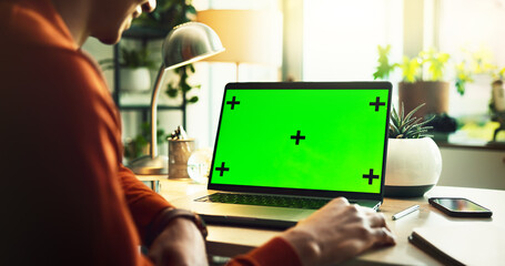Person, freelancer and laptop with green screen or mockup for online advertising, marketing or UI software at home office. Closeup, user or computer with technology display or tracking markers for UX