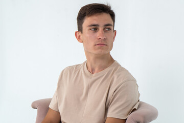 Young confident man sitting in armchair close-up on a white background