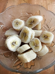 Banana pieces in insulated glass dish on wooden table 