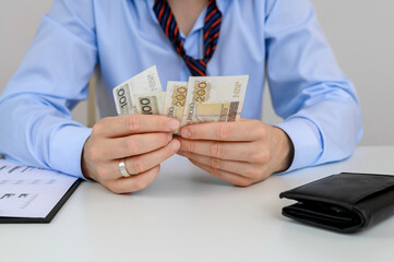 Kłopoty finansowe,  mężczyzna trzyma gotówkę w dłoni i liczy